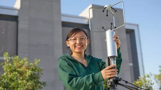 a woman wearing safety glasses holding a low carbon emissions product